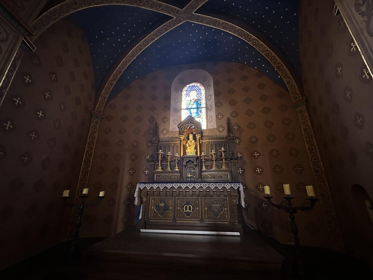 Candlesticks on a chapel altar beneath a starry blue ceiling at the Abbey of Abondance in the French Alps