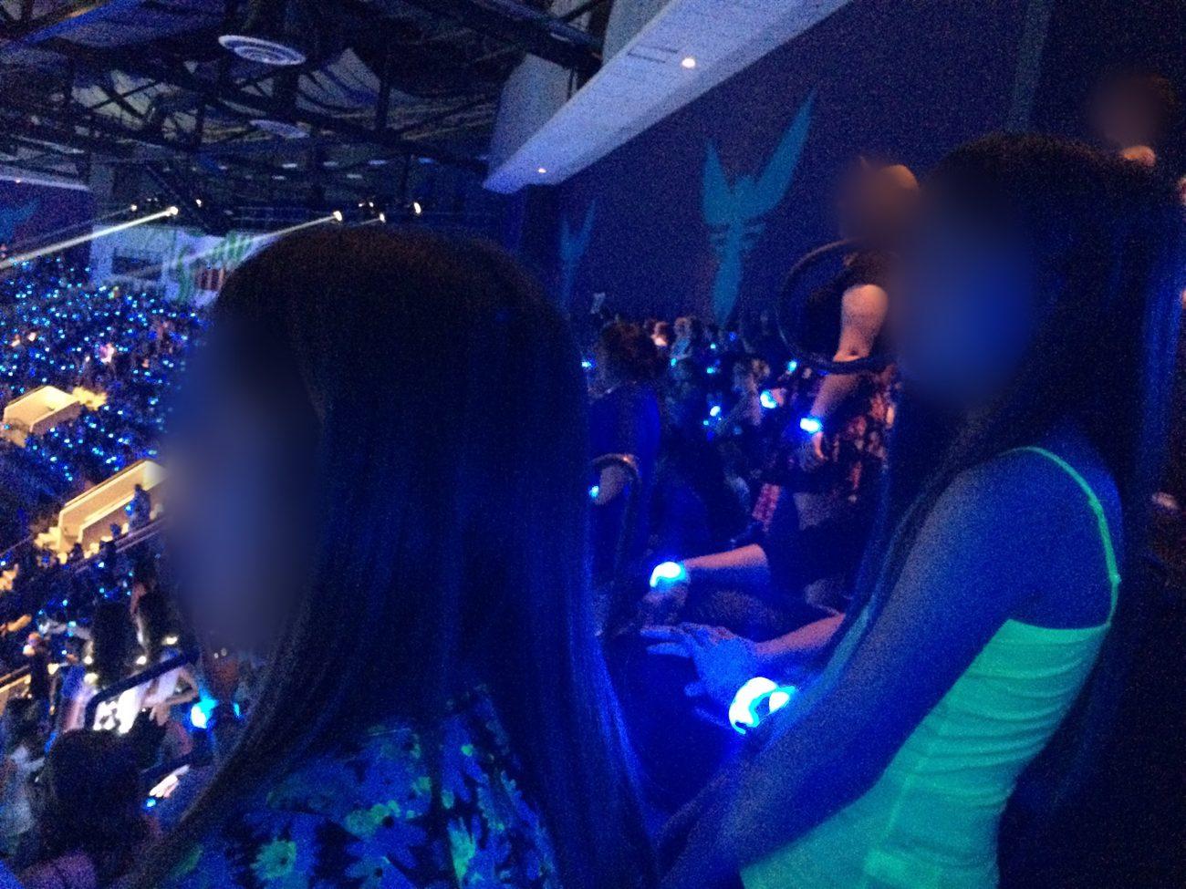Ashley’s stepdaughters watching Taylor Swift’s 1989 World Tour from the stands, glowing wristbands lit up blue, faces blurred