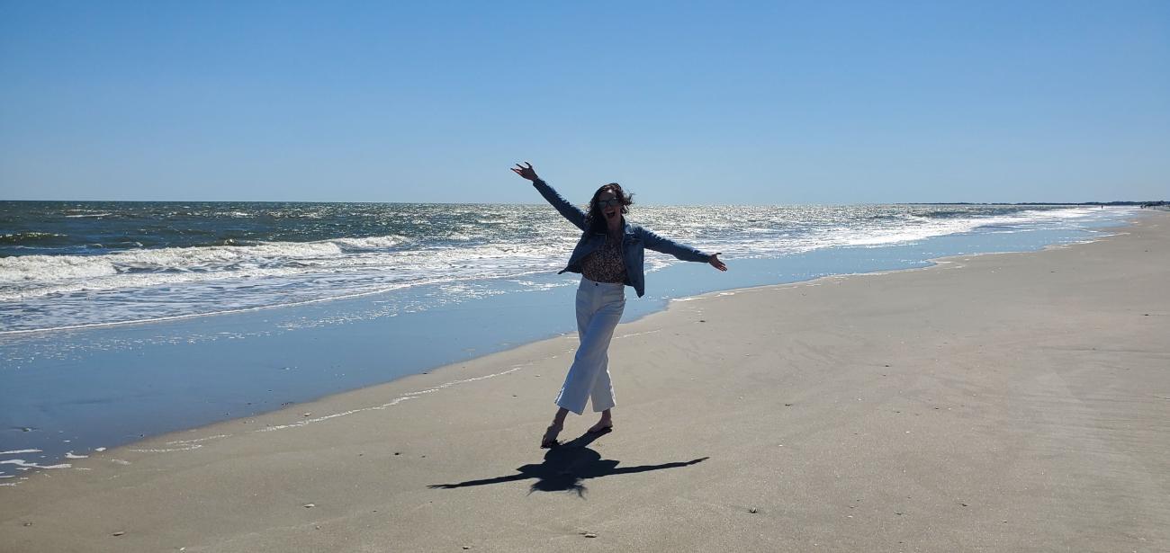 Ashley on the beach with her arms open