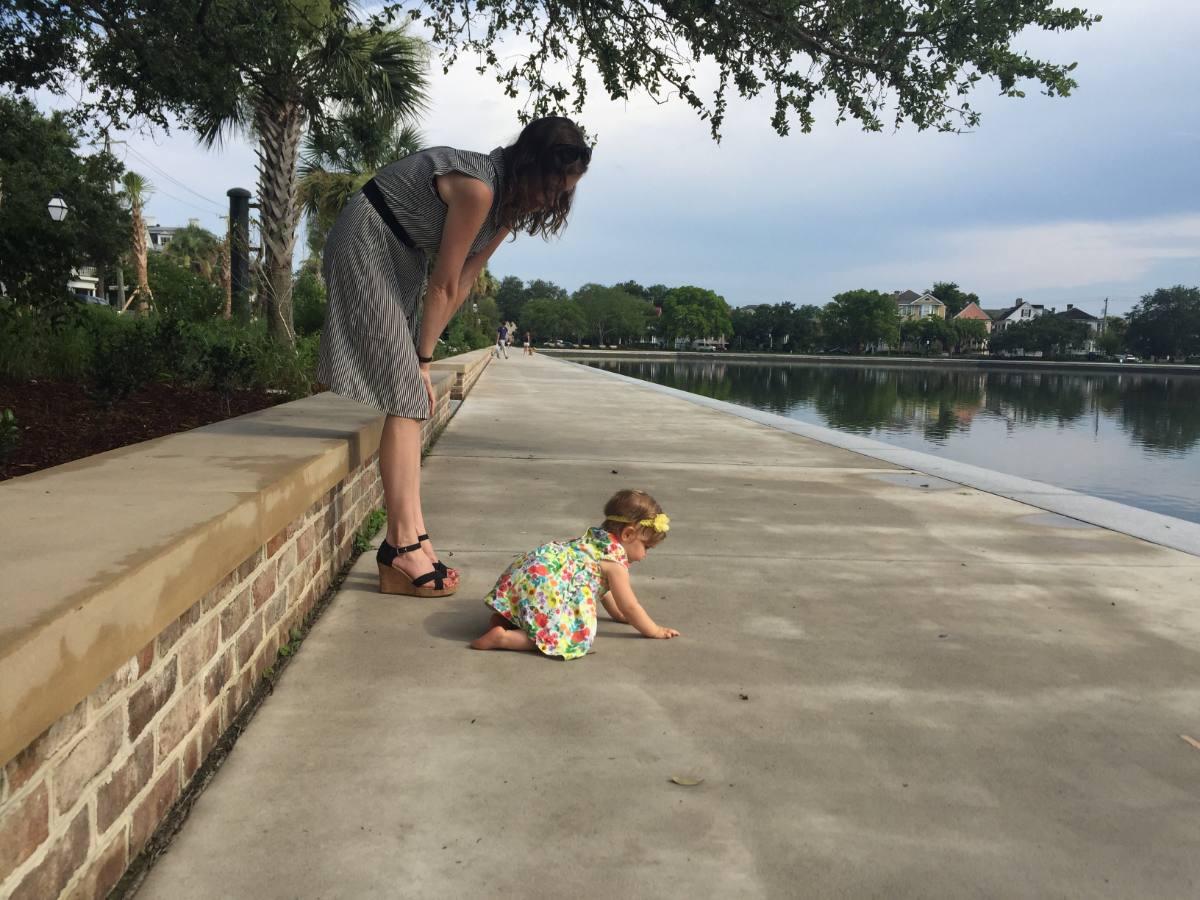 Ashley bending toward her daughter as a baby, beside Colonial Lake in Charleston