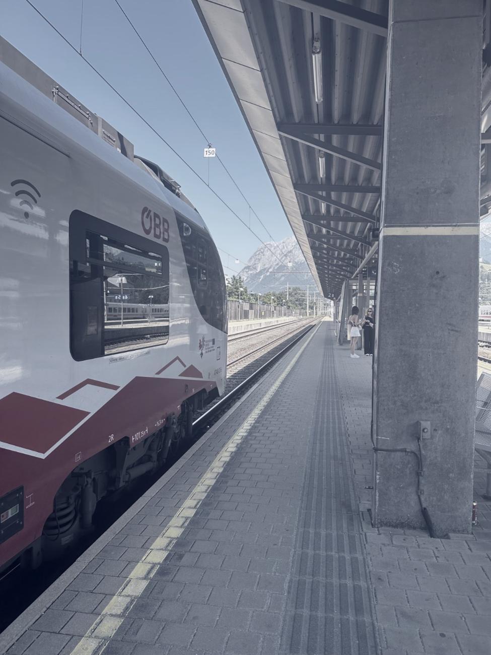 A station platform with an empty track and mountains beyond