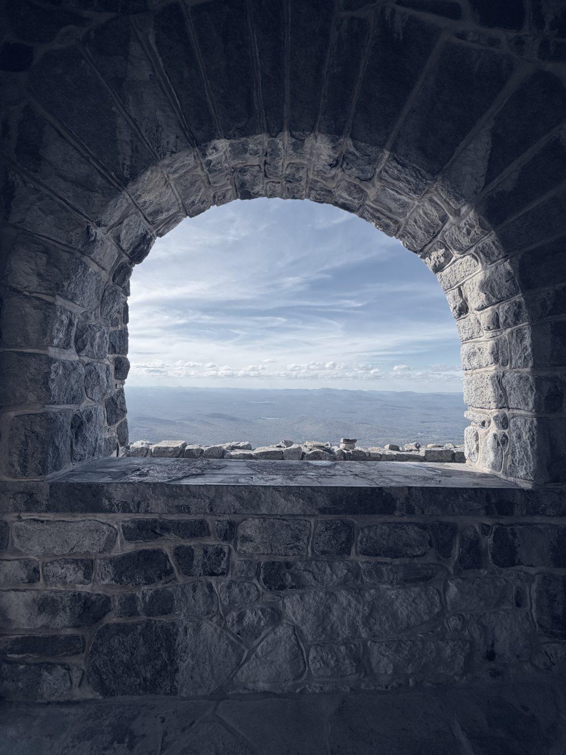 A stone arch window framing a wide mountain view