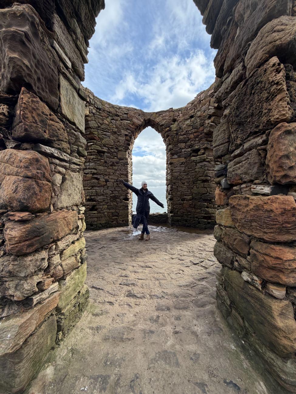 Ashley standing inside a coastal stone ruin in Scotland
