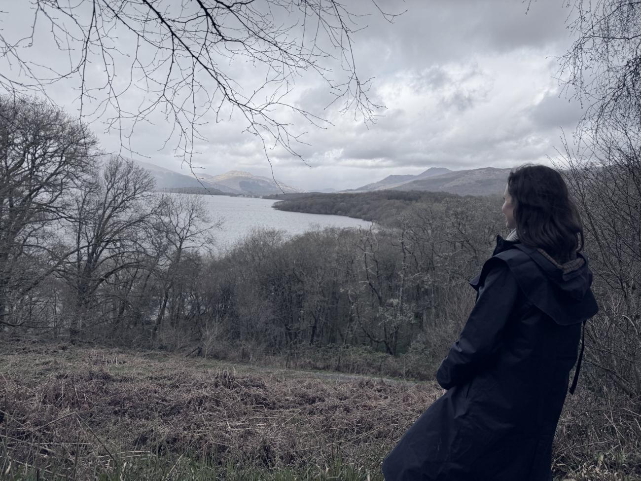 Ashley looking out over a loch toward distant mountains in Scotland