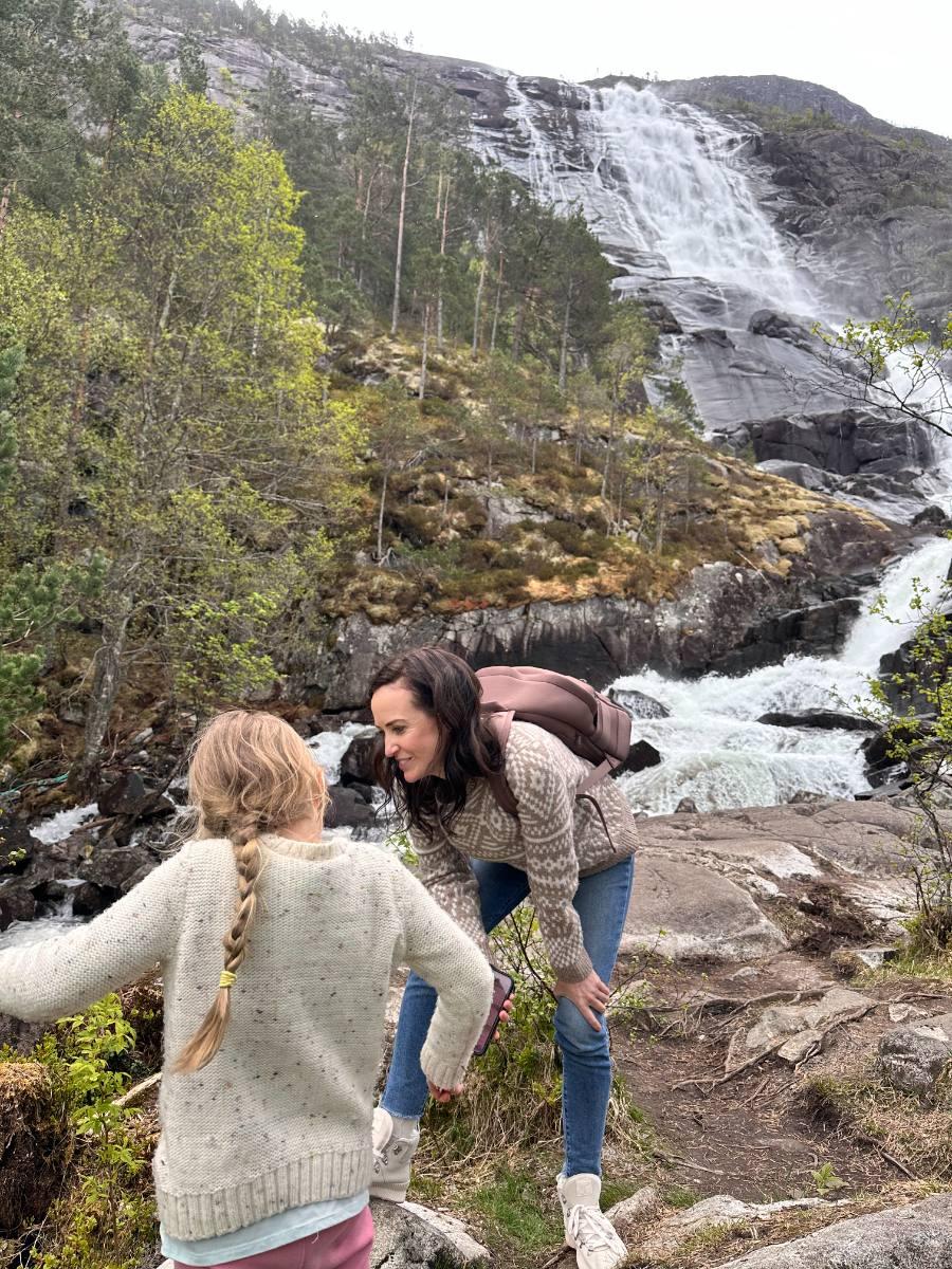 Ashley and her daughter at the foot of a waterfall in Norway