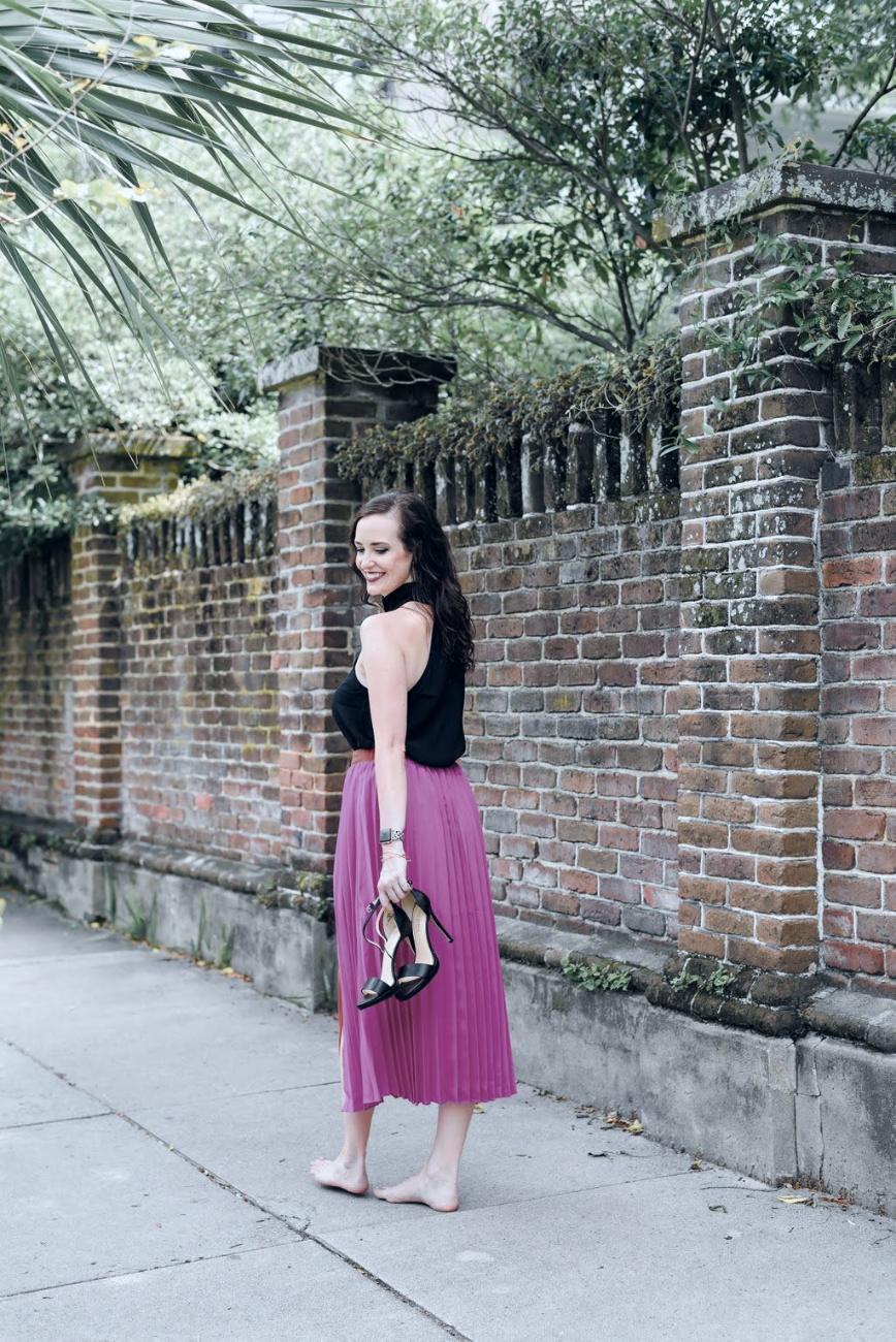Ashley Thiesen barefoot on a Charleston sidewalk, heels in hand