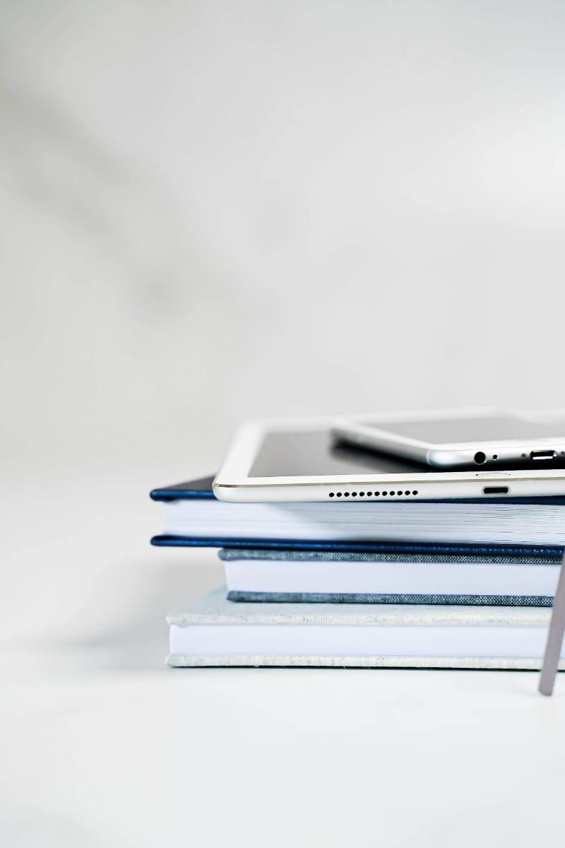 A stack of books, a notebook and a tablet