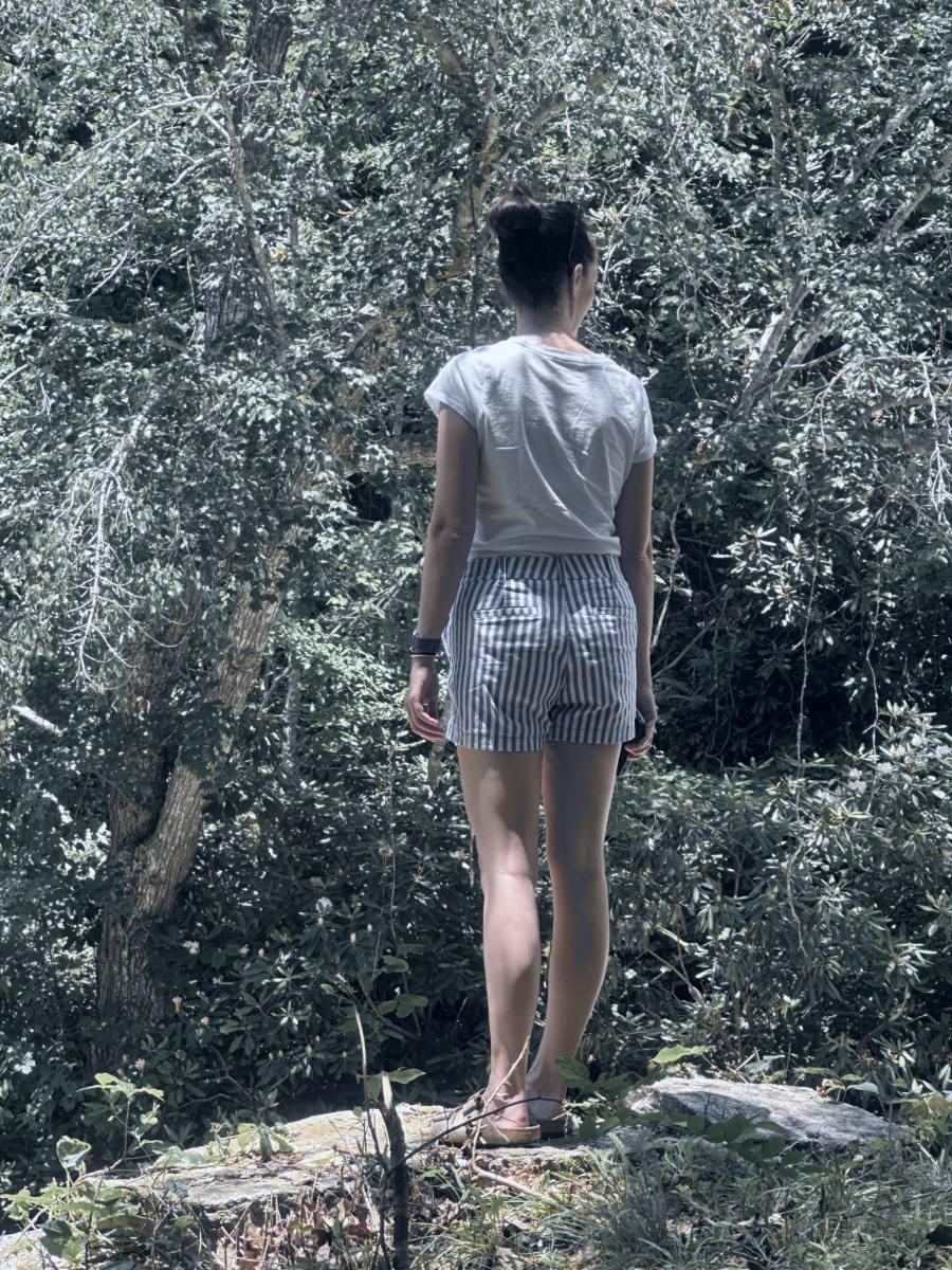Ashley Thiesen standing on a rock, facing into the trees